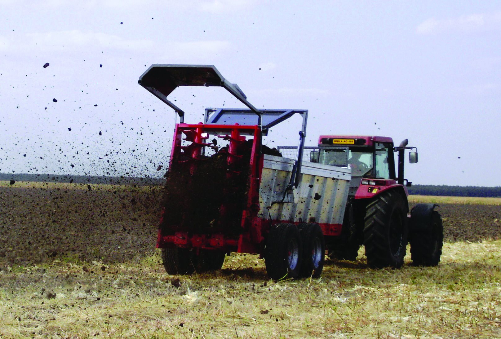Tractor spreading sewage sludge on farm land