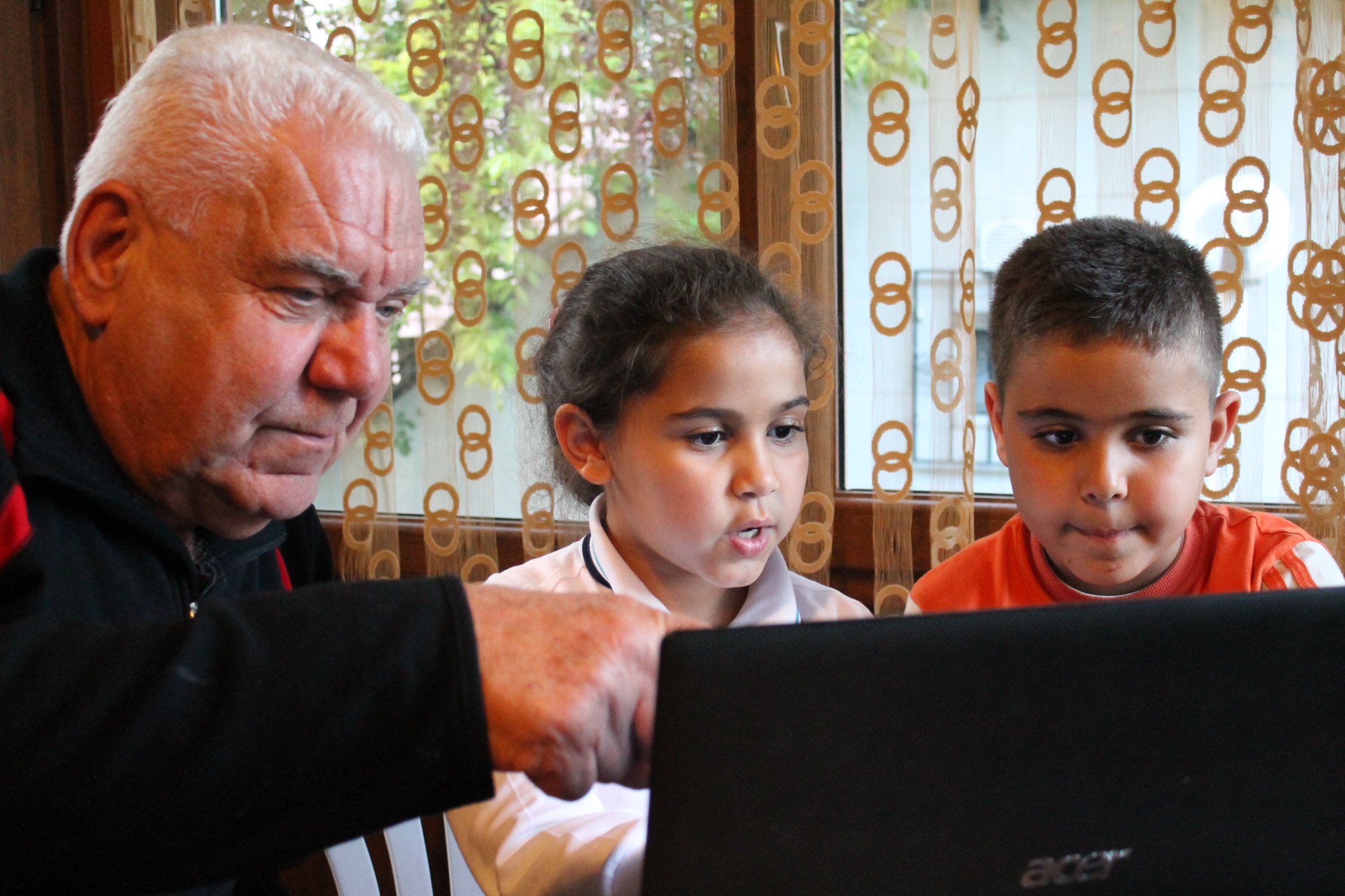 A grandfather with his grandchildren at a computer