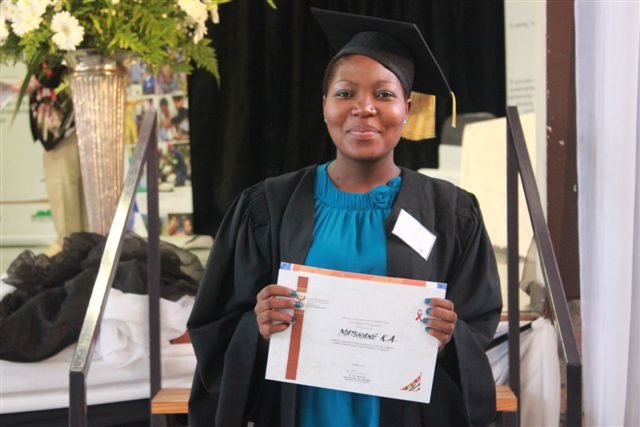 Community caregiver holds up Thogomelo training certificate at graduation