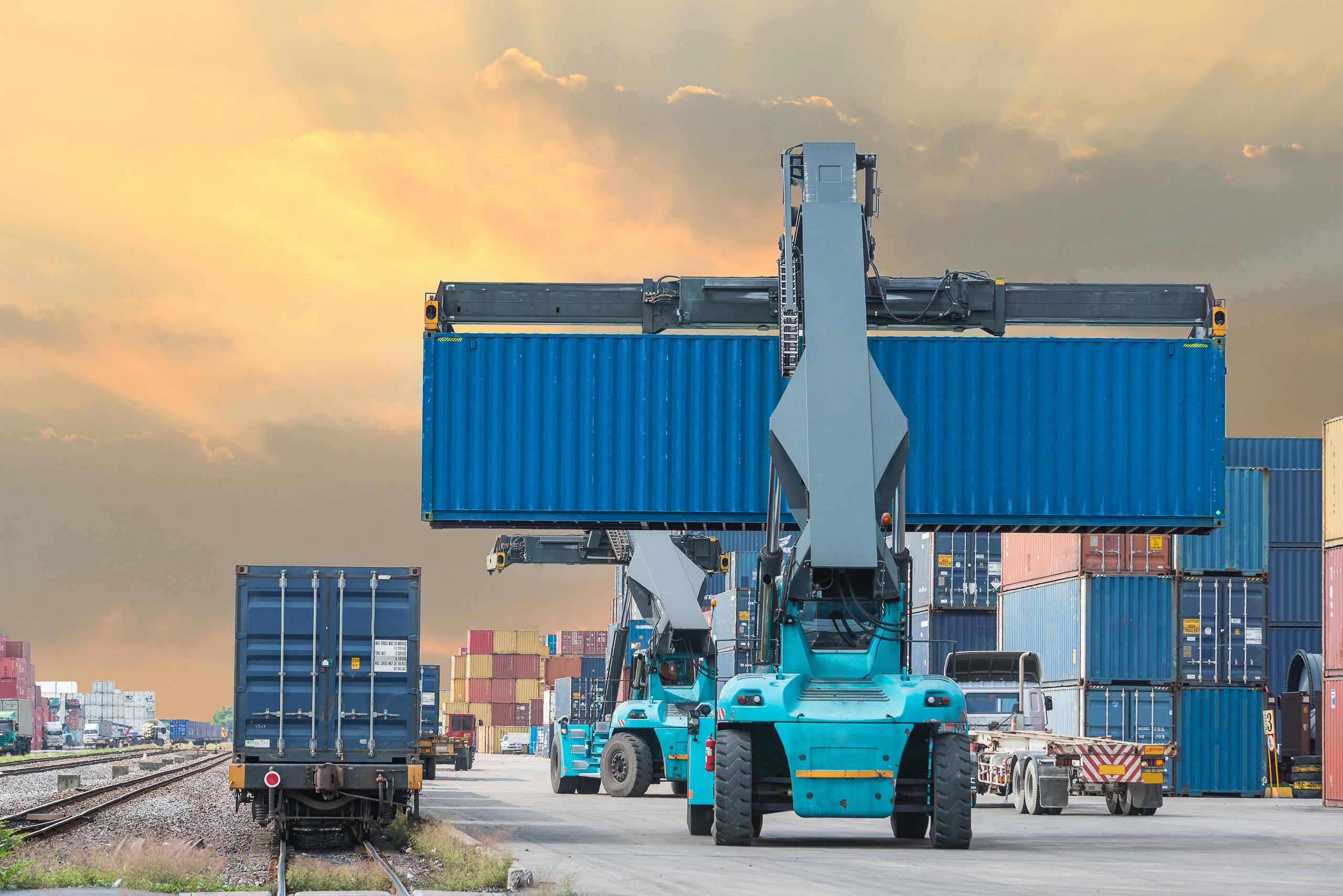 Forklift handling container box loading to freight train in import and export area at a port