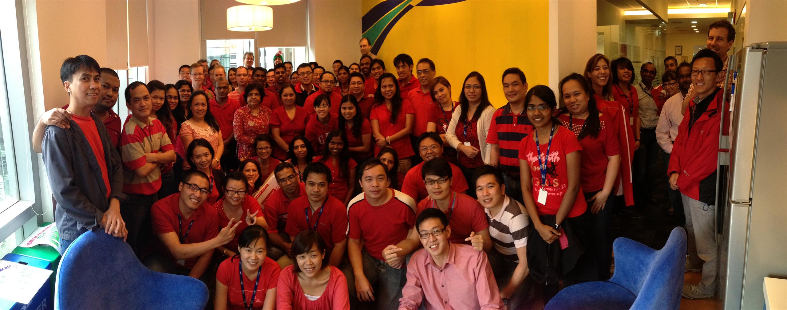 Foto da equipe da Mott MacDonald no escritório de Singapura posando em trajes vermelhos