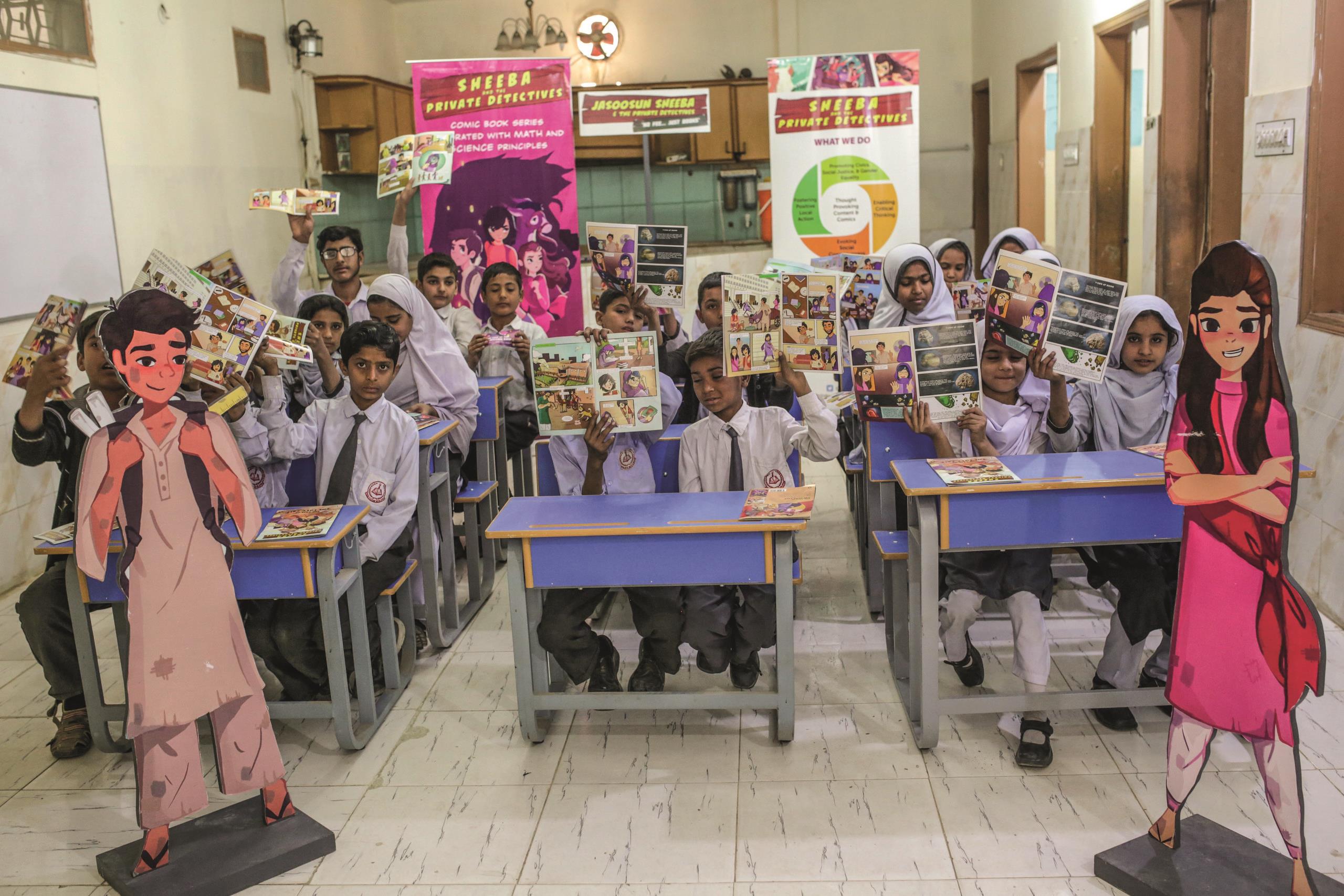 Students holding up open pages of the AzCorp Sheeba comic book as part of The Pakistan Education Innovation Fund.
