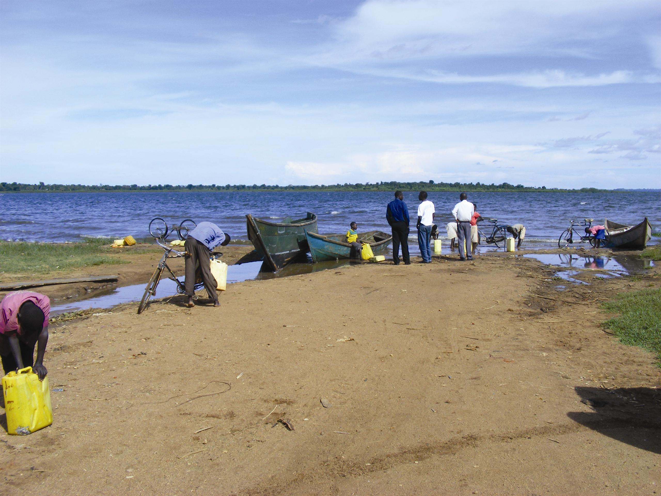Local people by side of lake with wooden boat on shore