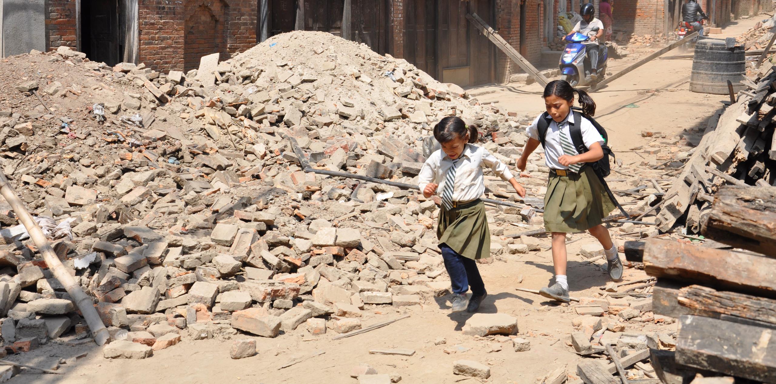 Young students pick their way through the rubble of their town as they head back to school for the first time since the earthquakes in Nepal.