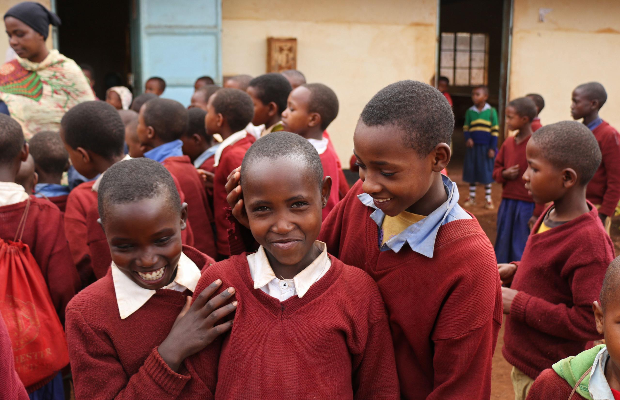 School children from Nyoka primary school in Tanzania, smiling whilst looking at the camera.