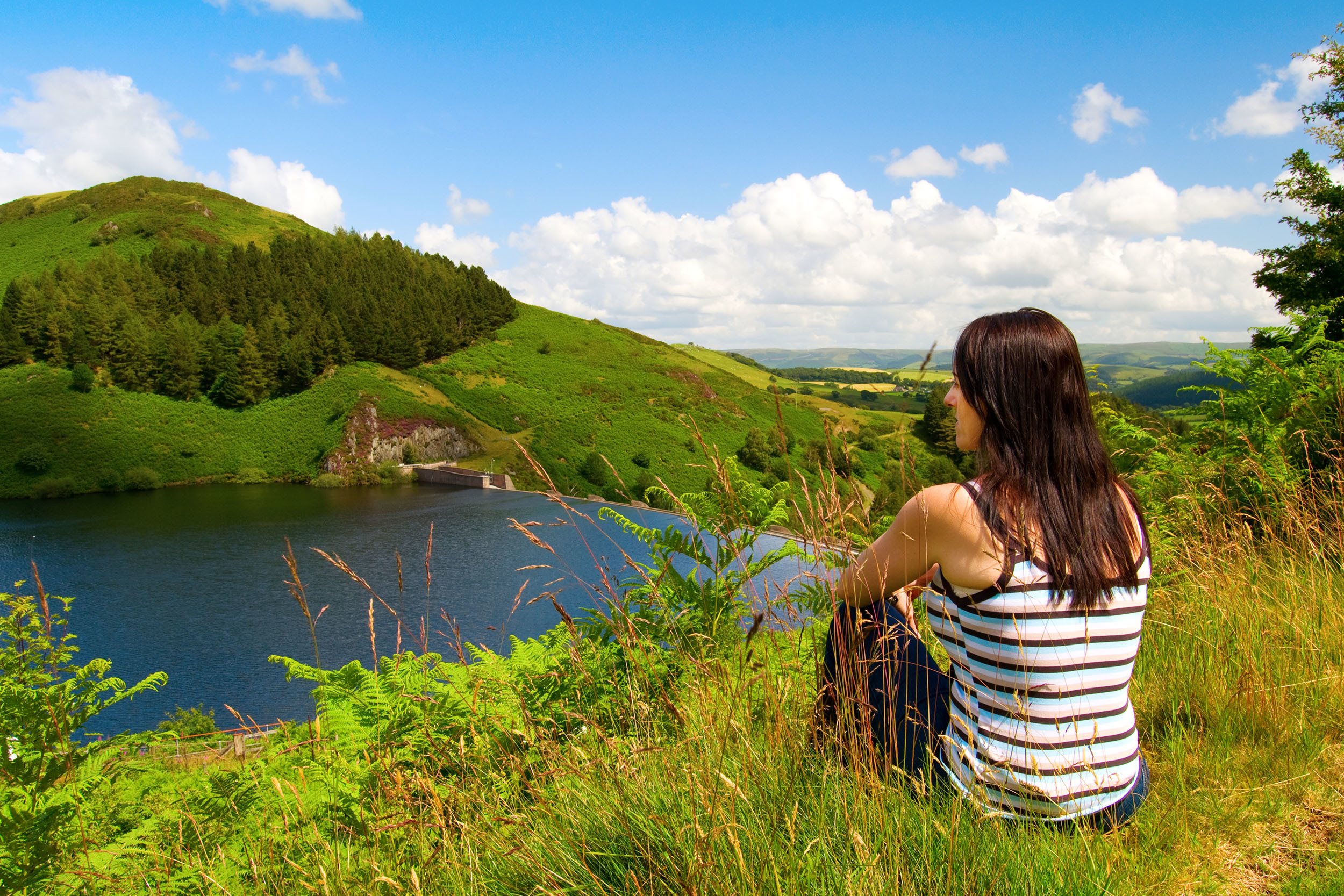 A woman sat looking over the Llyn Clywedog Reservoir