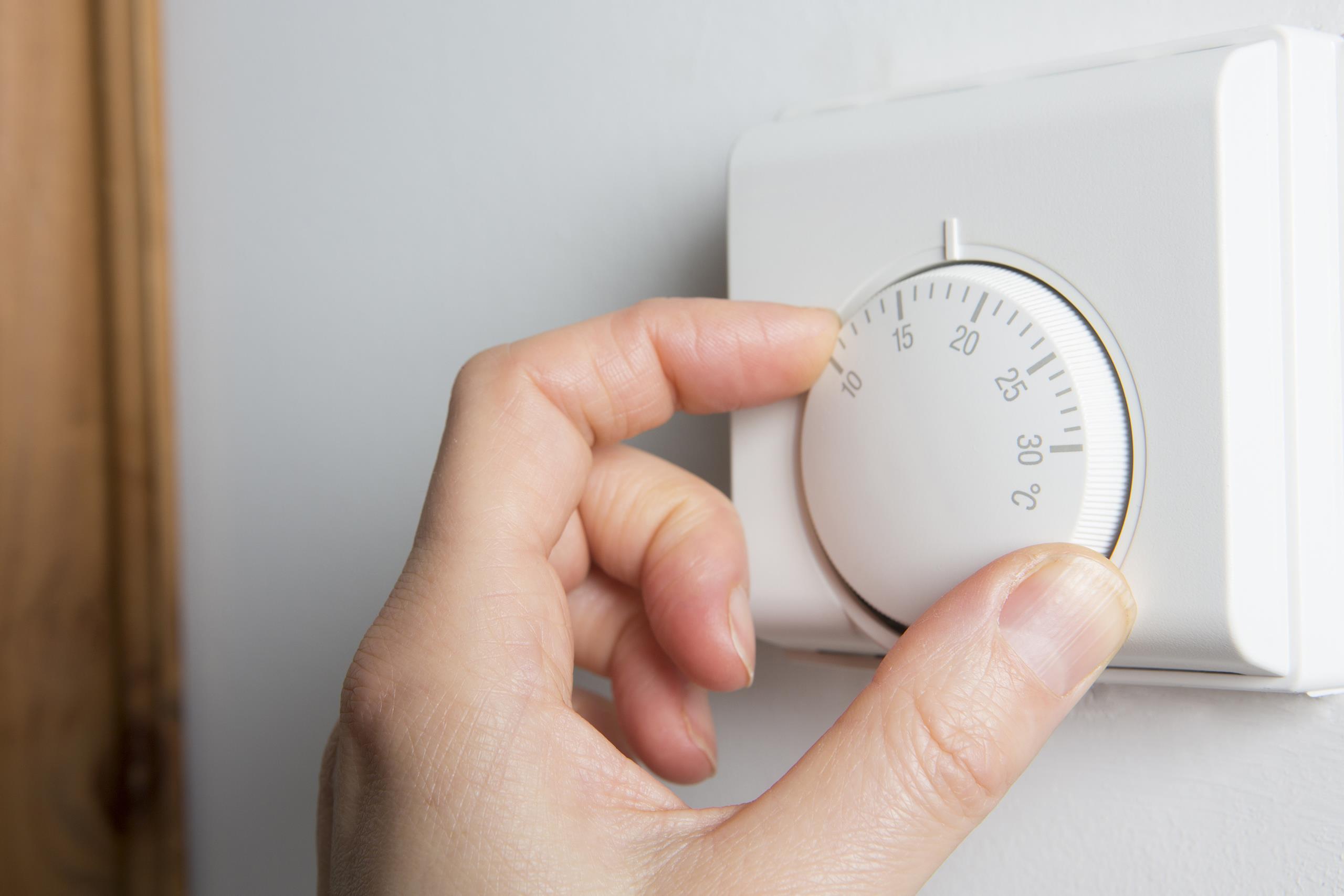 A lady's hand turning down a thermostat