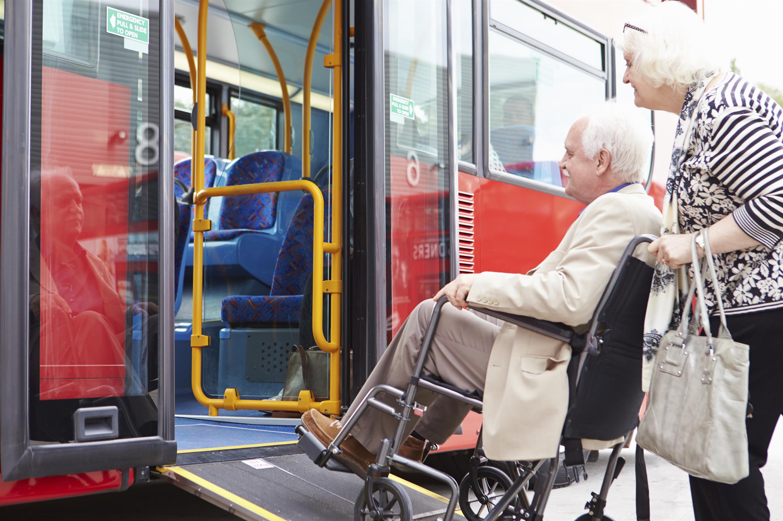Man in a wheelchair getting support to get onto a bus