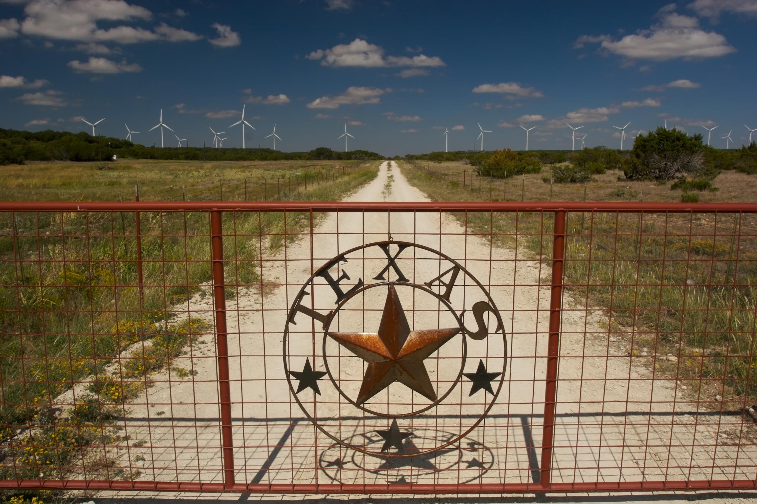 Closed Texas emblem gate, which leads up to a wind farm