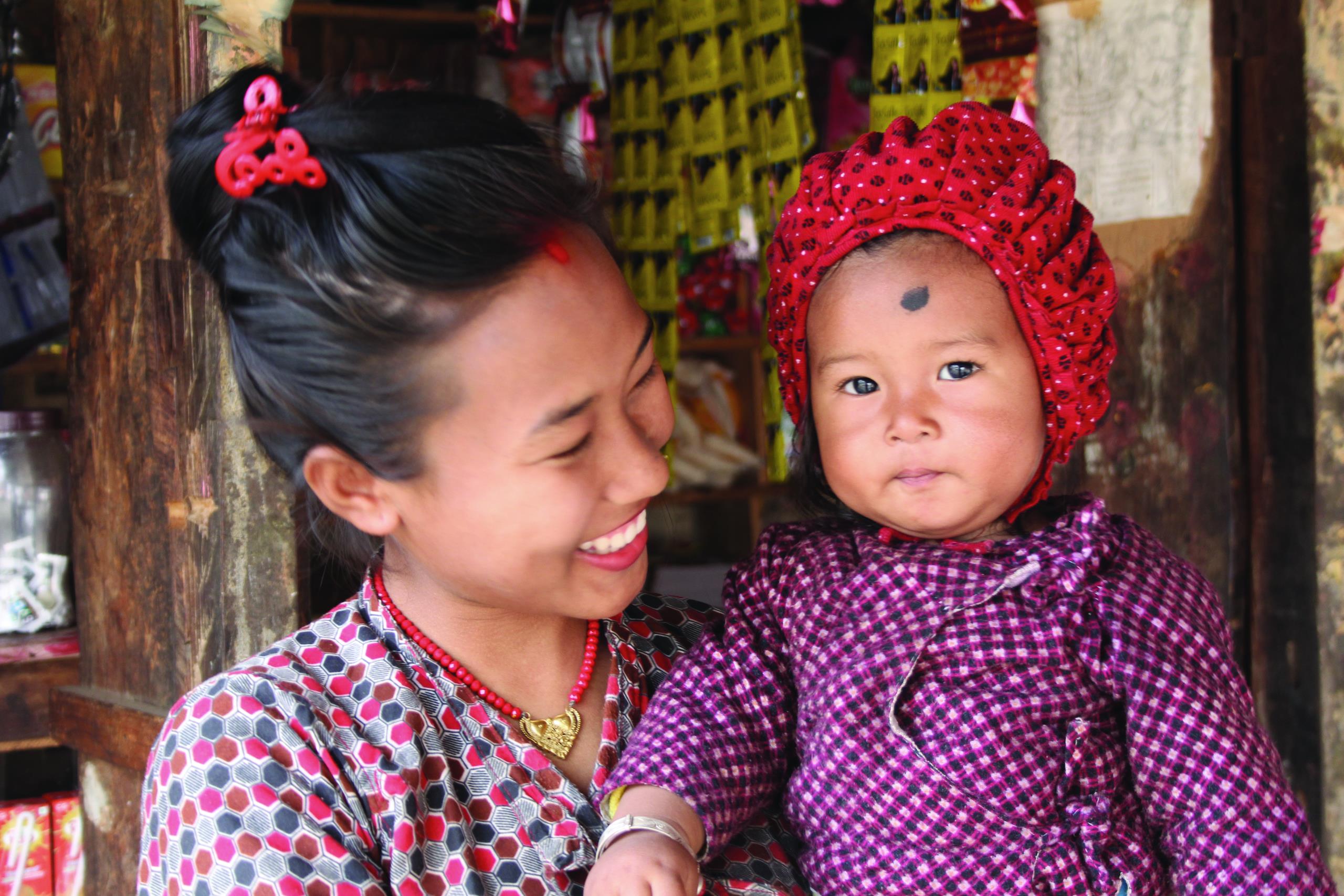 Lady smiling whilst holding her child in Nepal