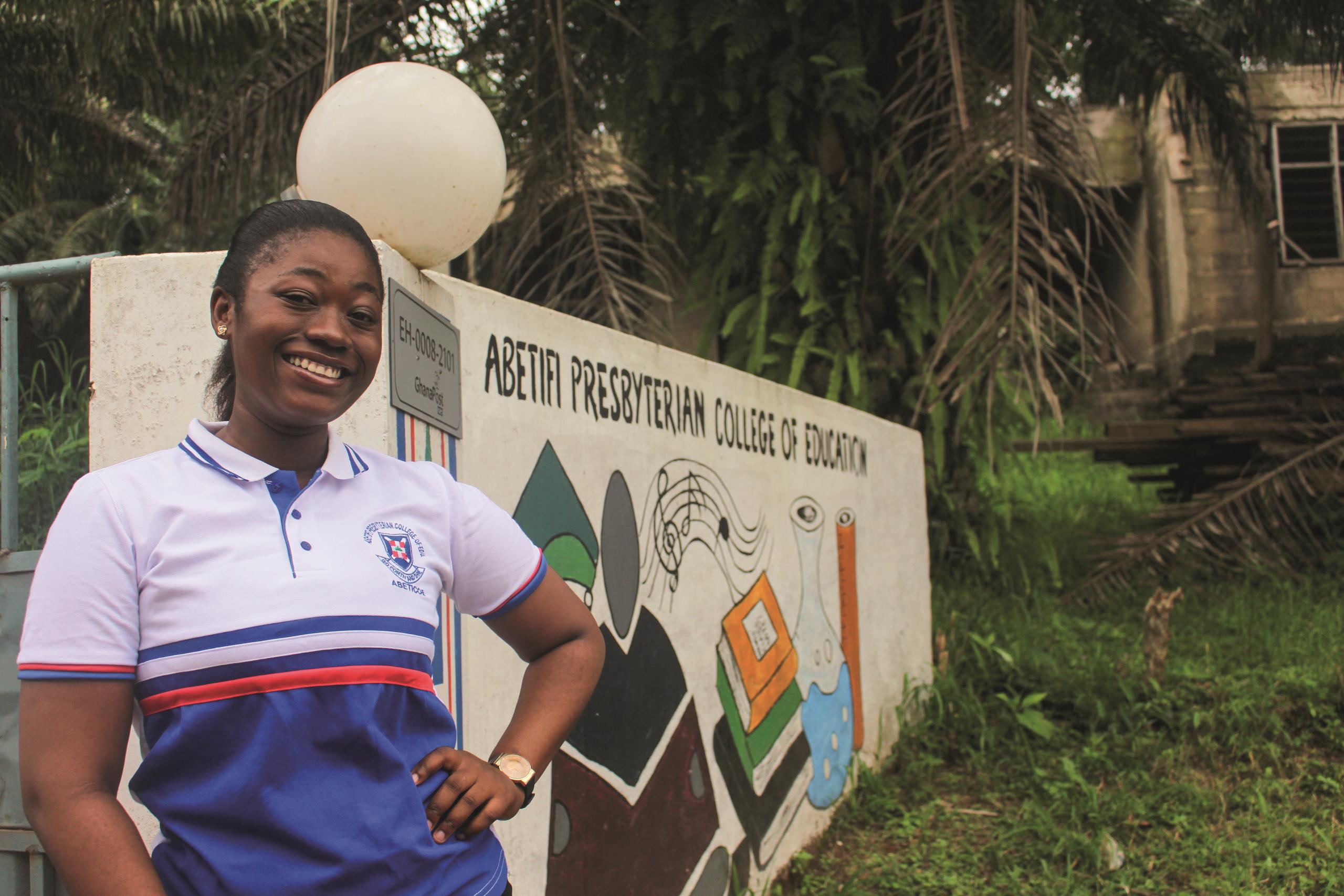 Gifty Mensah, graduate teacher, smiling in front of a wall at Abetifi Presbyterian College of Education
