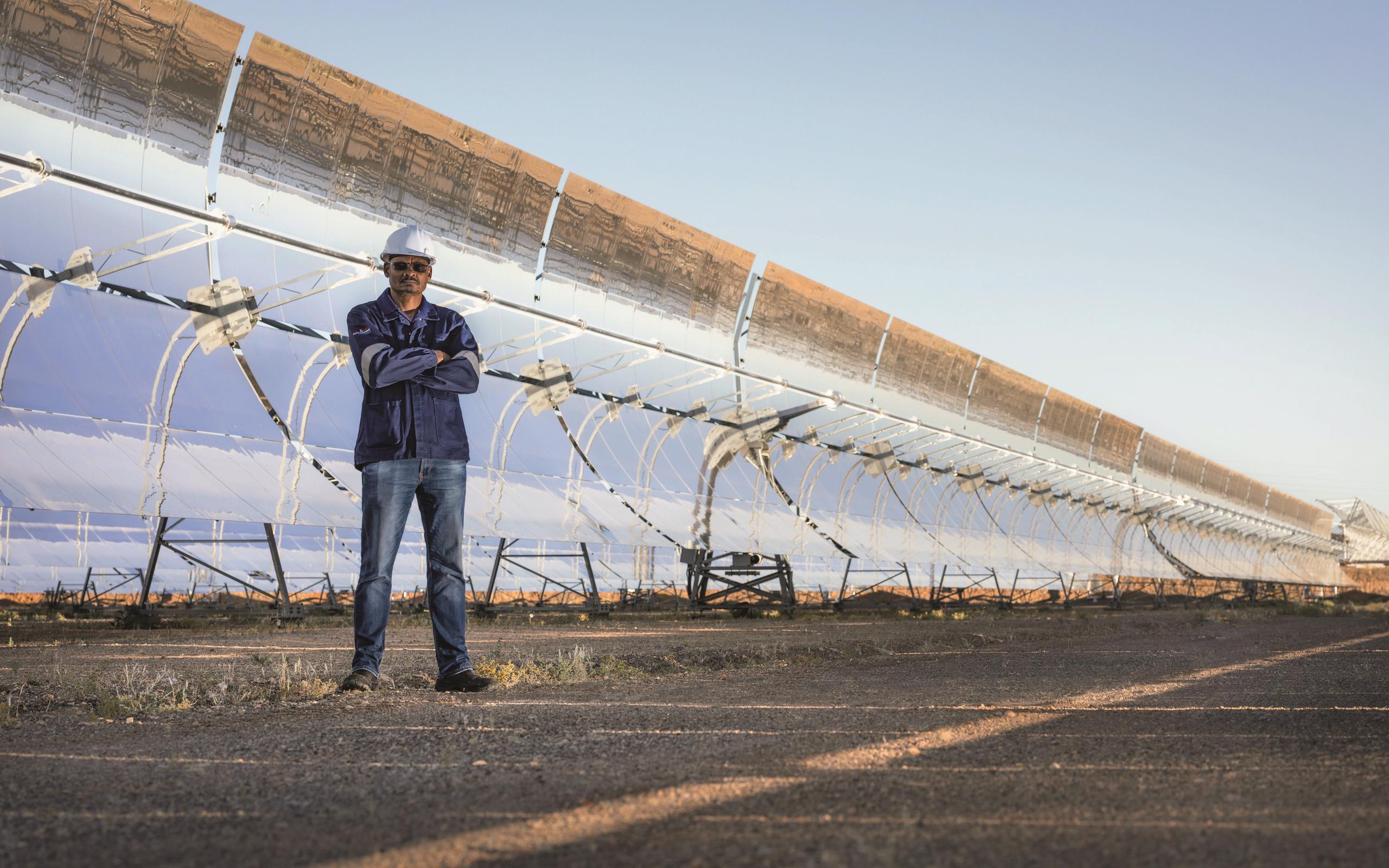 Greg March standing in front of solar panels at the KaXu Solar One solar thermal park in South Africa