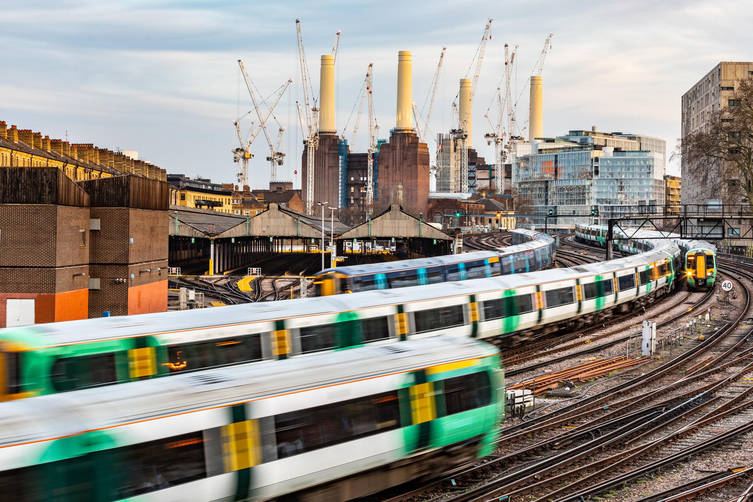 Trains travelling on tracks in front of Battersea power station