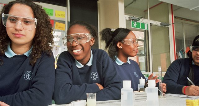 image of schoolgirls conducting science experiment in classroom