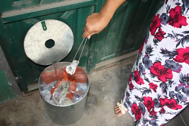 image showing woman placing used syringe in a bin