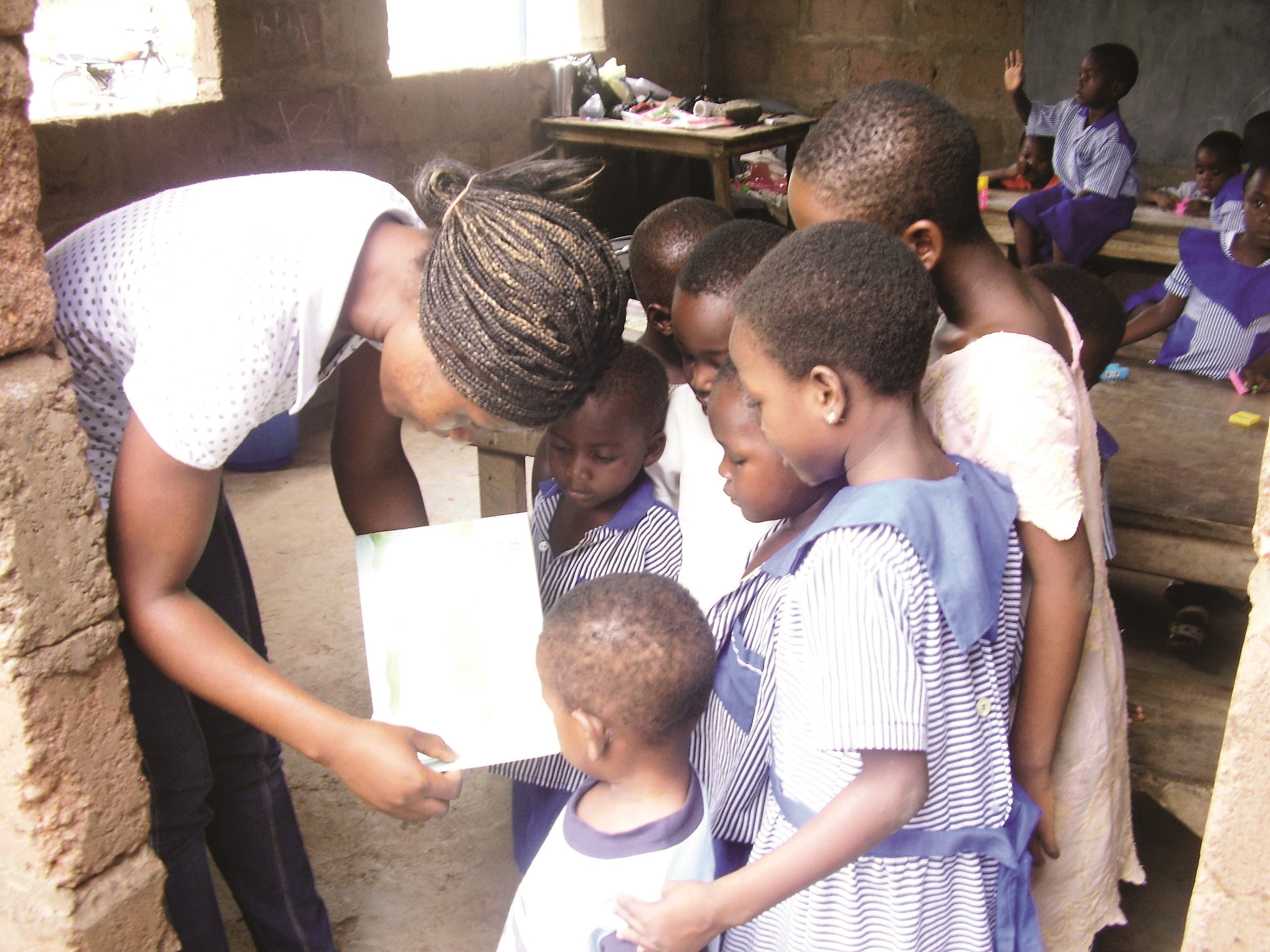 image of teacher looking at a book with a group of children